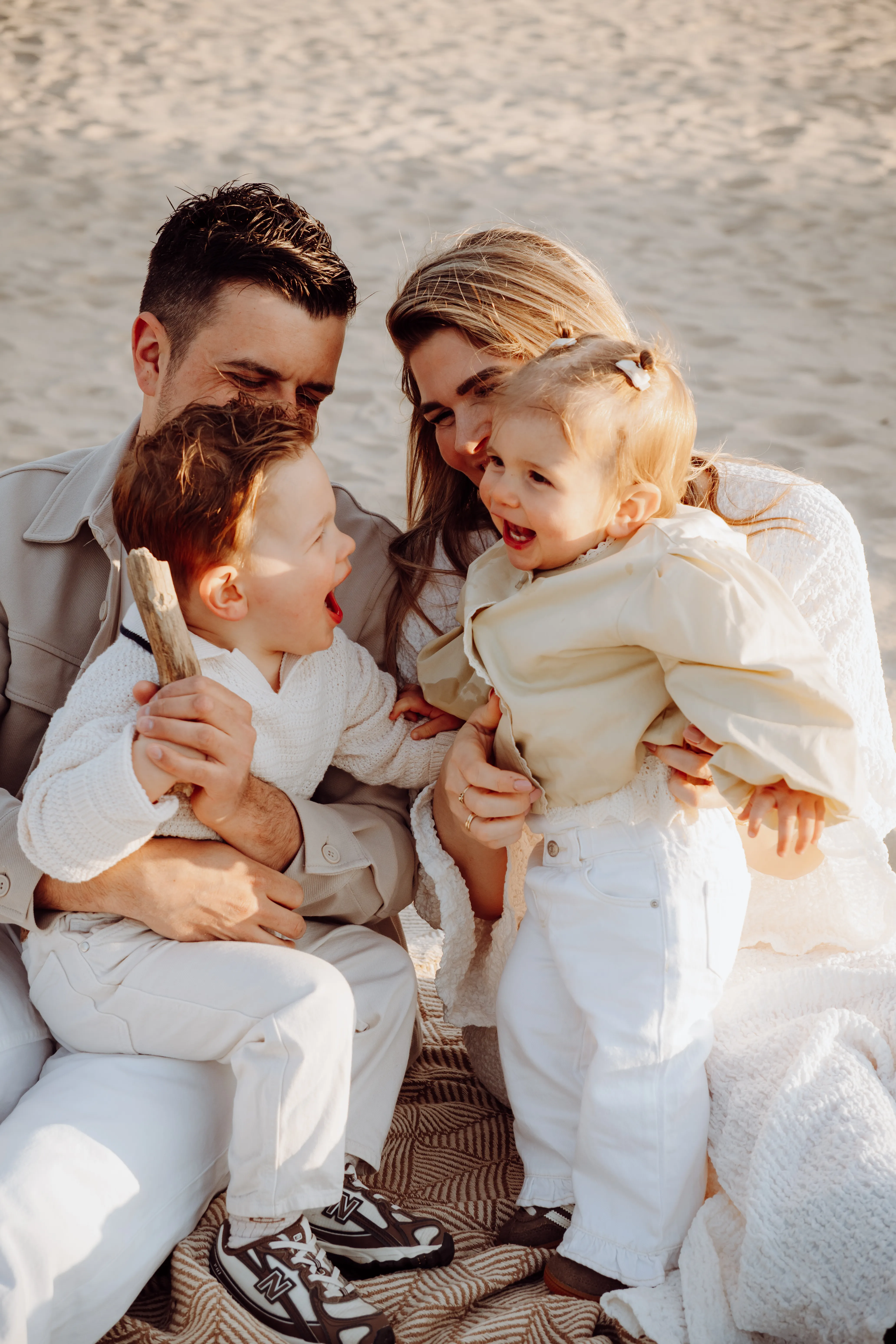 Speels gezinsmoment op het strand met twee lachende peuters