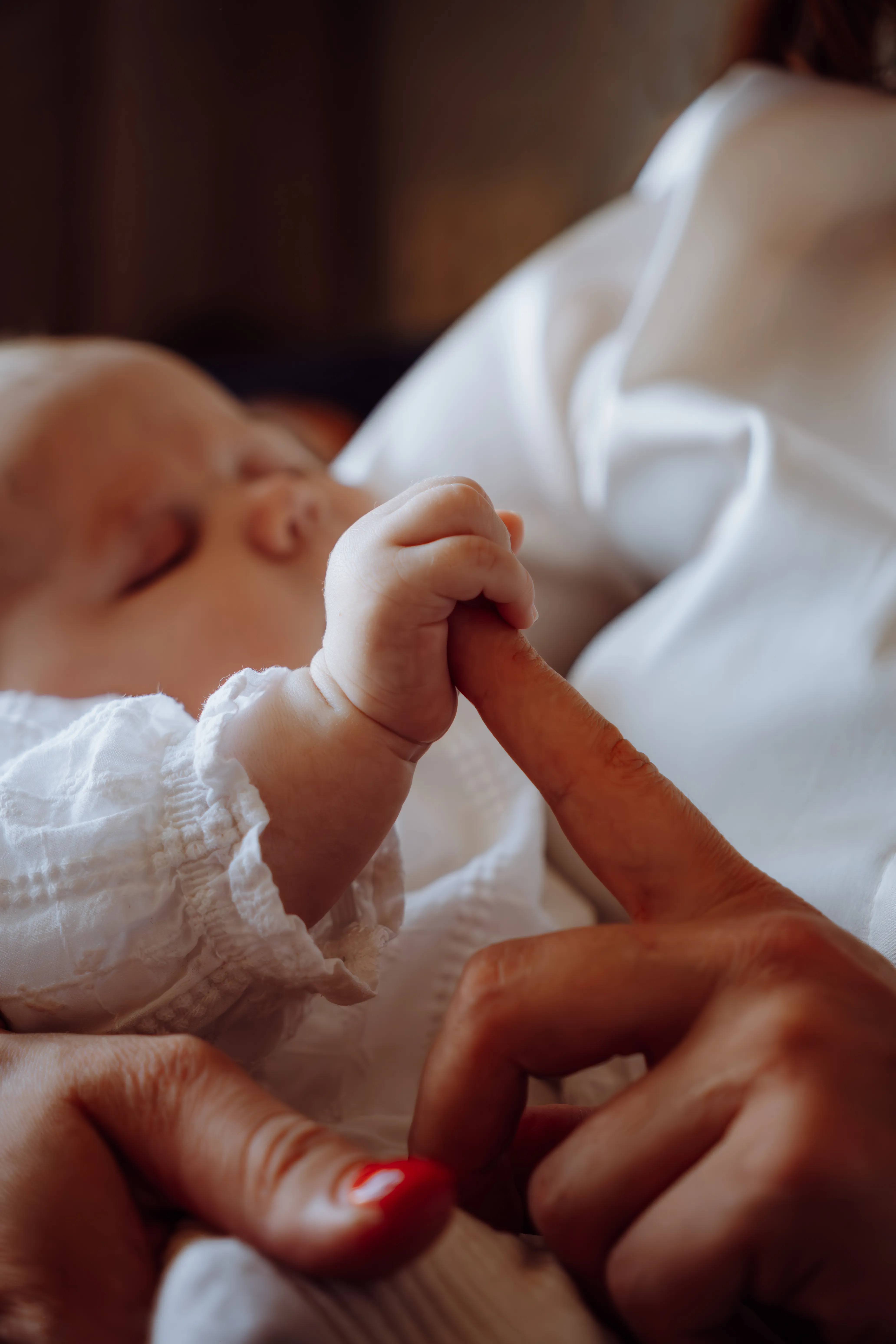 Slapende pasgeboren baby houdt de vinger van een ouder vast in een zachte close-up