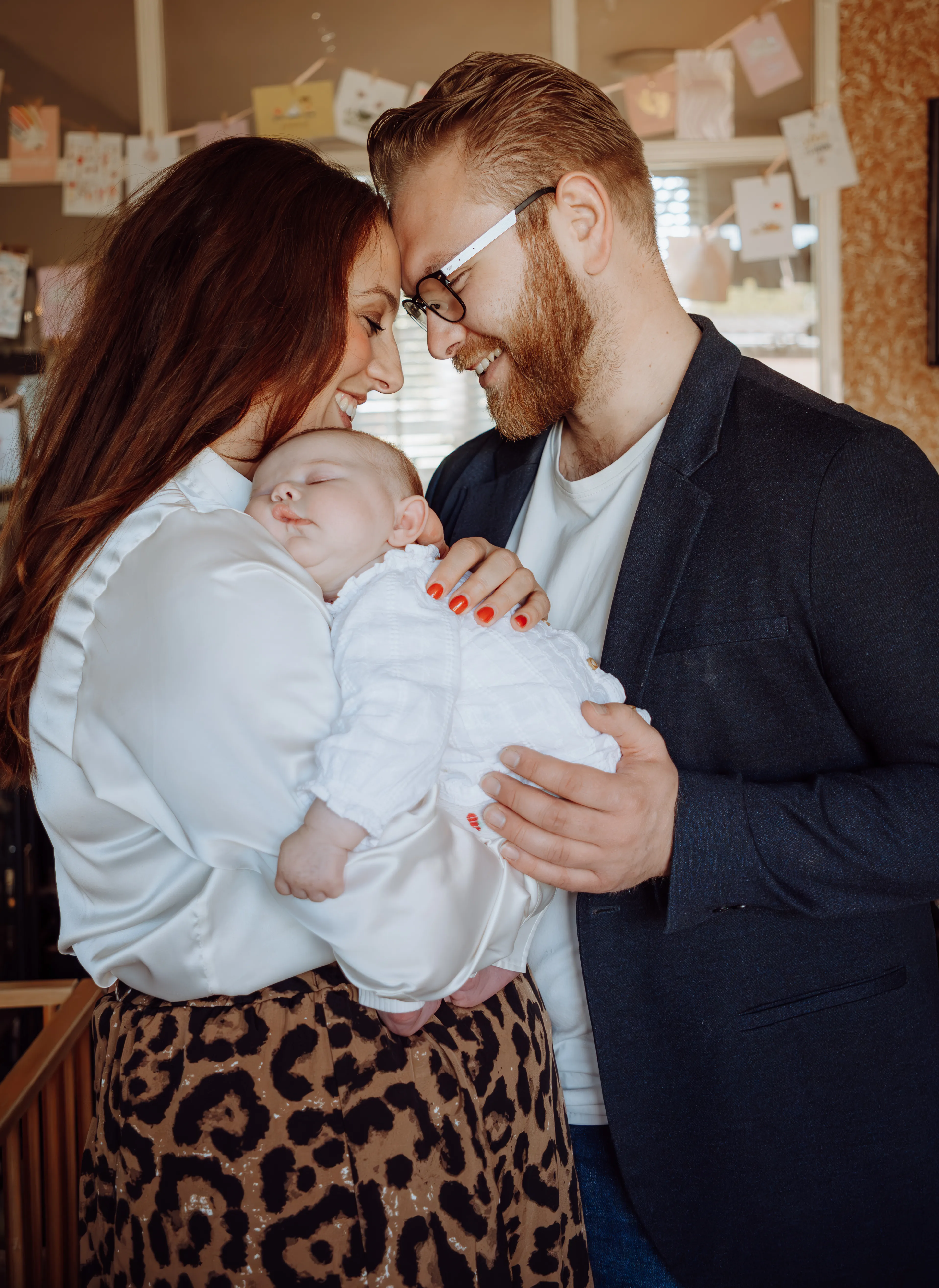 Ouders buigen innig over hun slapende pasgeboren baby in huis