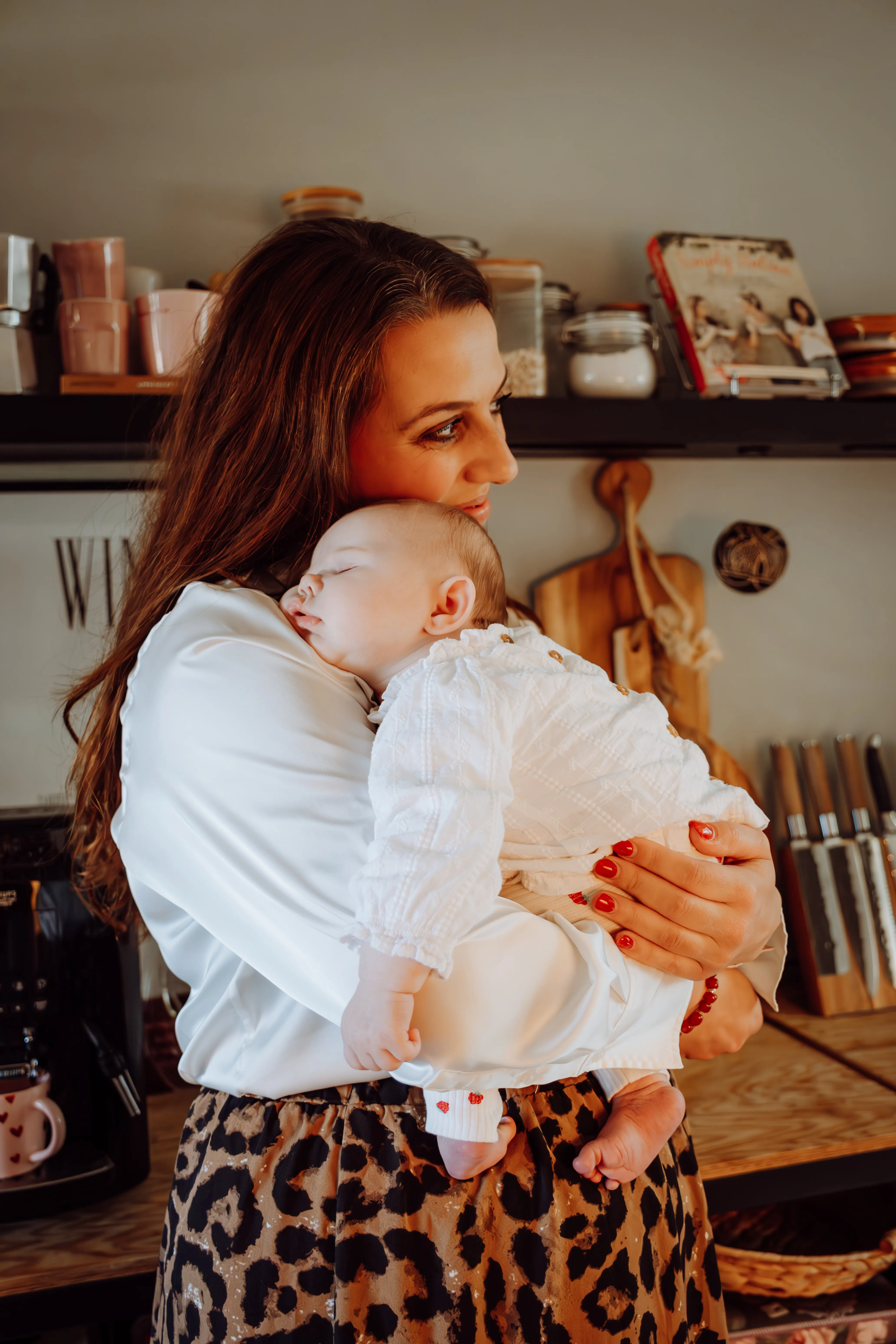 Moeder knuffelt haar pasgeboren baby dicht tegen zich aan in de keuken thuis