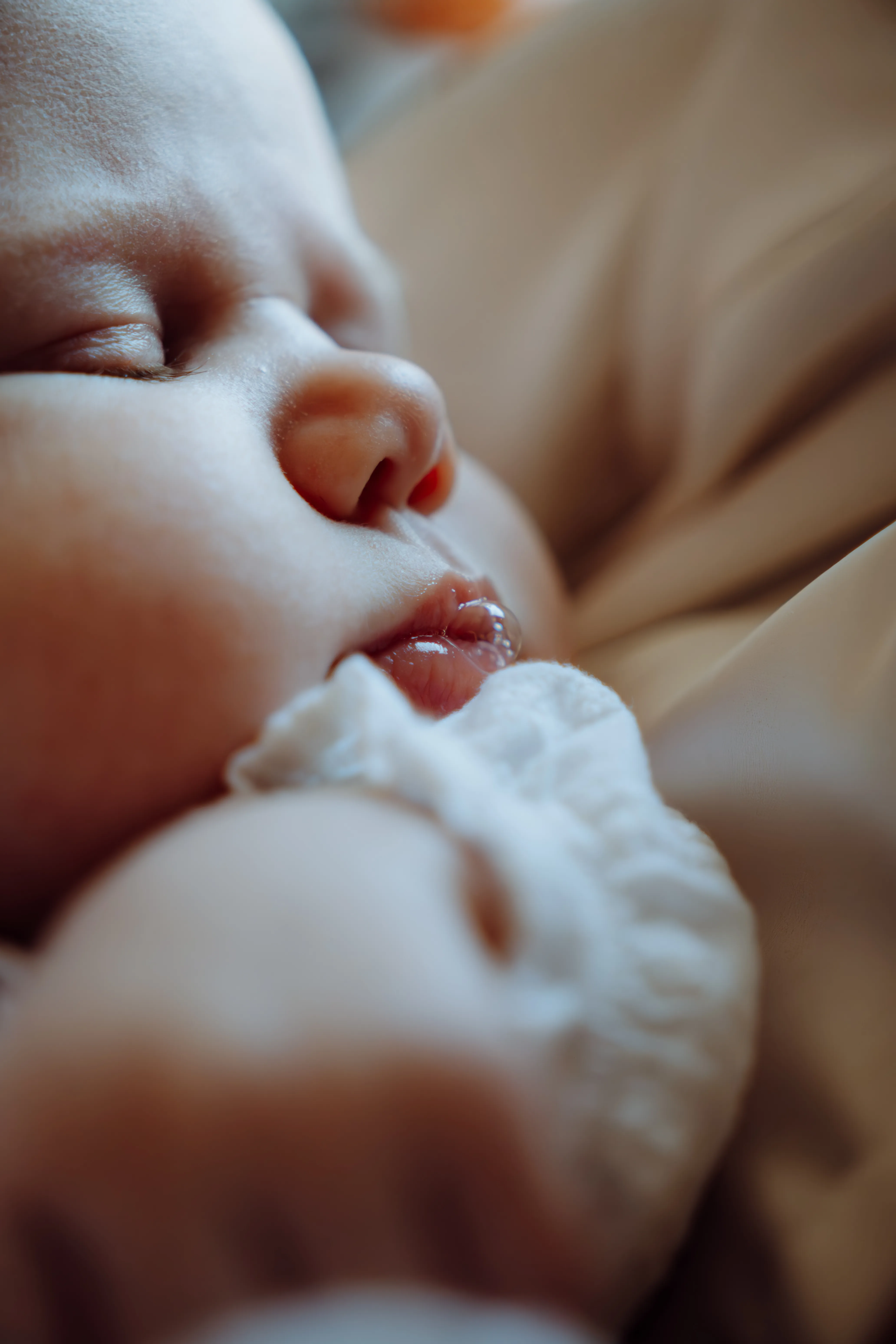 Slapende pasgeboren baby met uitgestoken tongetje in een warme close-up