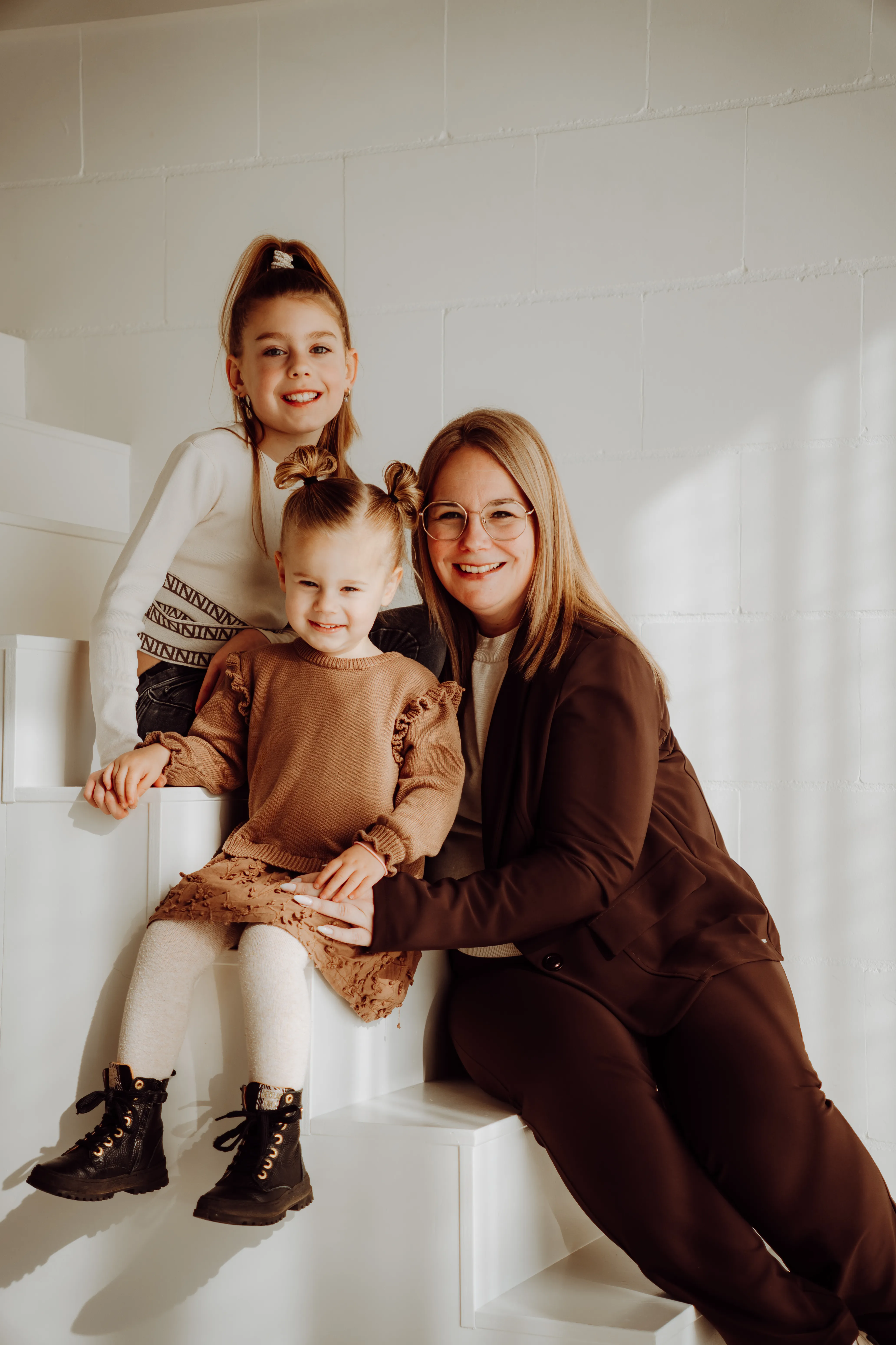Vrouw poseert samen met twee kinderen tegen een lichte studiowand